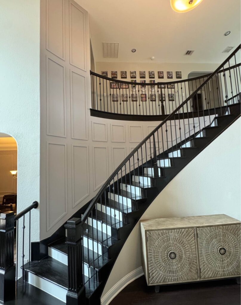 White accent wall with decorative panel molding along staircase in Houston home
