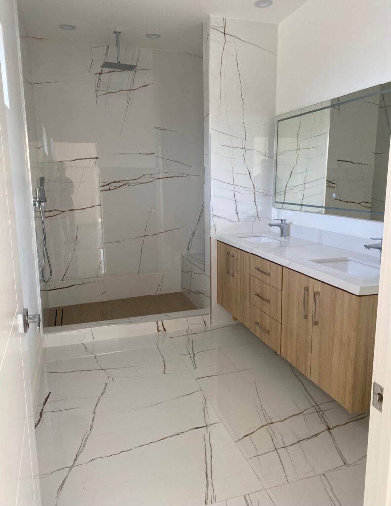 Bathroom remodeling with walk-in shower, custom wood vanity, double sink, large mirror, and marble-look tile in Houston home
