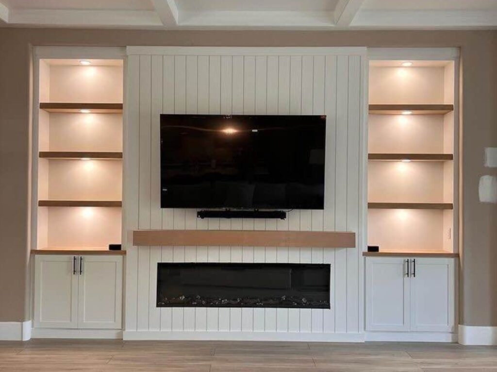 Custom media wall with TV, electric fireplace, and built-in shelves in Houston home