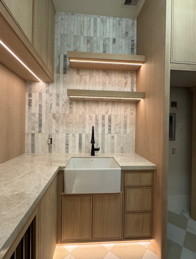Laundry room remodeling with wood cabinets, sink, tile backsplash, and LED lighting in Houston home