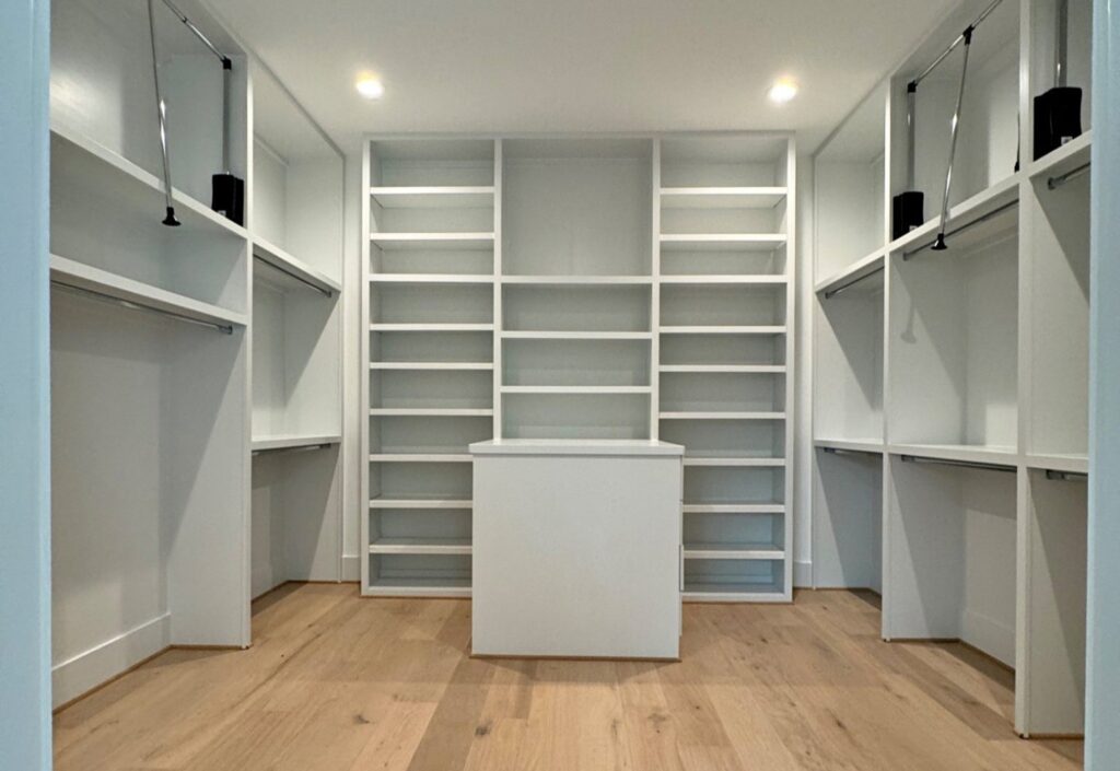 White walk-in closet with custom shelves, hanging rods, and center island in Houston home